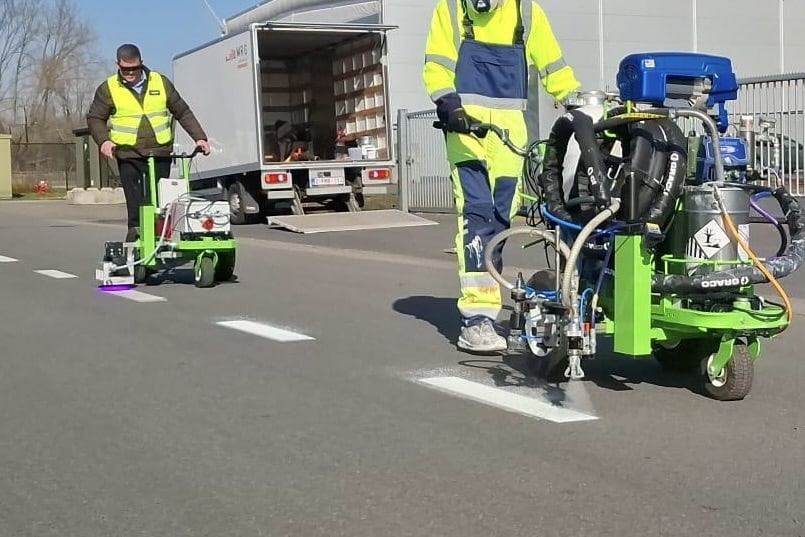 W&auml;hrend der Testphase: Die vordere Maschine spr&uuml;ht den neuen KNEHO-Lack auf, die hintere h&auml;rtet ihn innerhalb von Sekunden per LED-Licht aus. Foto: KNEHO