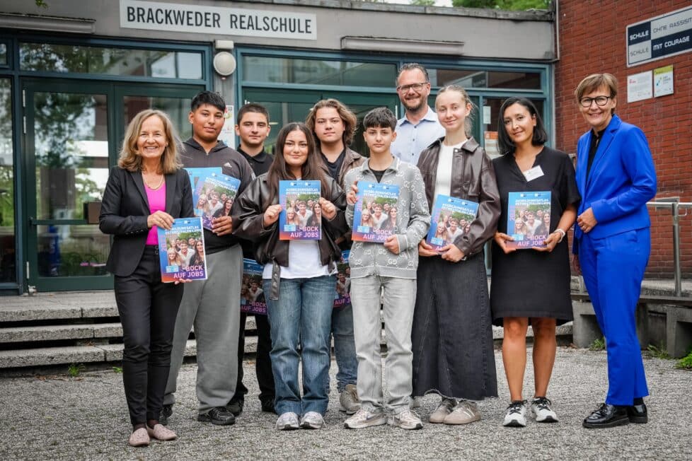 Übergabe der ersten Exemplare des IHK-Ausbildungsatlas 2027: Stellvertretend für alle allgemeinbildenden Schulen in Ostwestfalen haben IHK-Hauptgeschäftsführerin Petra Pigerl-Radtke (links) und Ute Horstkötter-Starke (rechts), IHK-Geschäftsführerin Berufliche Bildung, den Ausbildungsatlas an Schülerinnen und Schüler der Brackweder Realschule in Bielefeld sowie Schulleiter Armin Trojahn (hinten) und die Studien- und Berufswahlkoordinatorin Hilal Aslami (Zweite von rechts) überreicht. Foto: Tilo Sommer/IHK Ostwestfalen